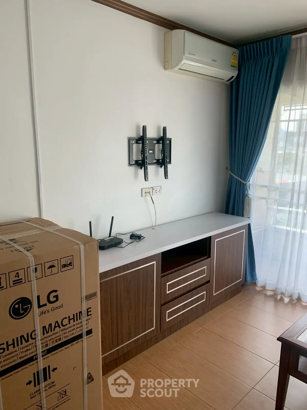 Modern interior with air conditioning and TV mount, featuring stylish curtains and wooden cabinetry.