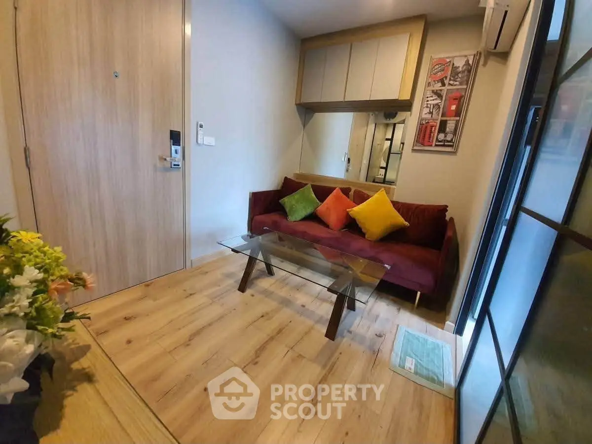 Cozy living room with vibrant cushions and glass coffee table in modern apartment.