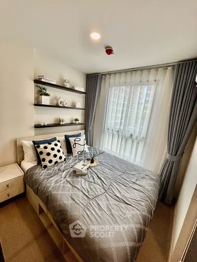 Modern bedroom with stylish decor and large window offering natural light in urban apartment.