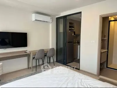 Modern studio apartment with sleek interior design, featuring a compact kitchen and cozy living area.