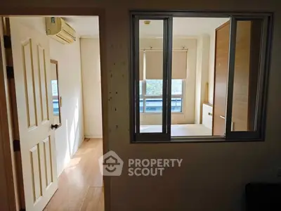 Cozy bedroom with wooden flooring and large window offering natural light.
