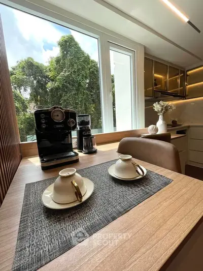 Modern kitchen with coffee machine and elegant table setting by large window.