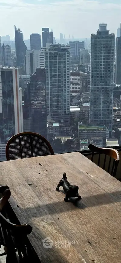Stunning cityscape view from a high-rise apartment with a rustic wooden dining table.