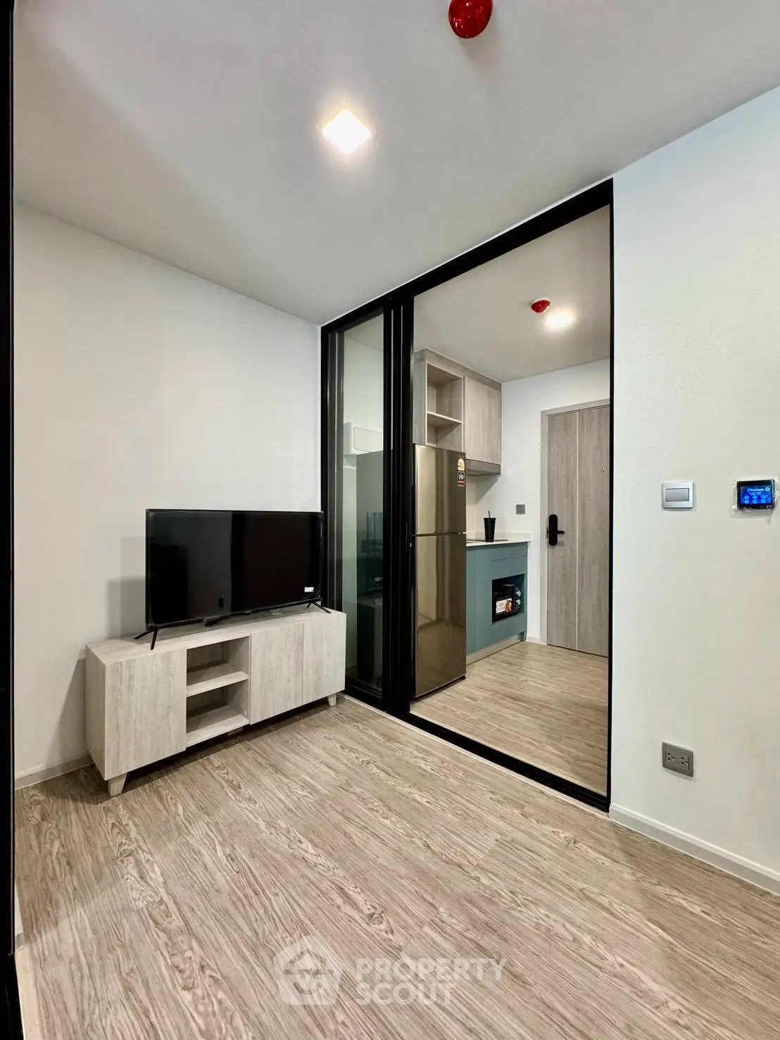 Modern living room with sleek TV stand and glass partition in stylish apartment.