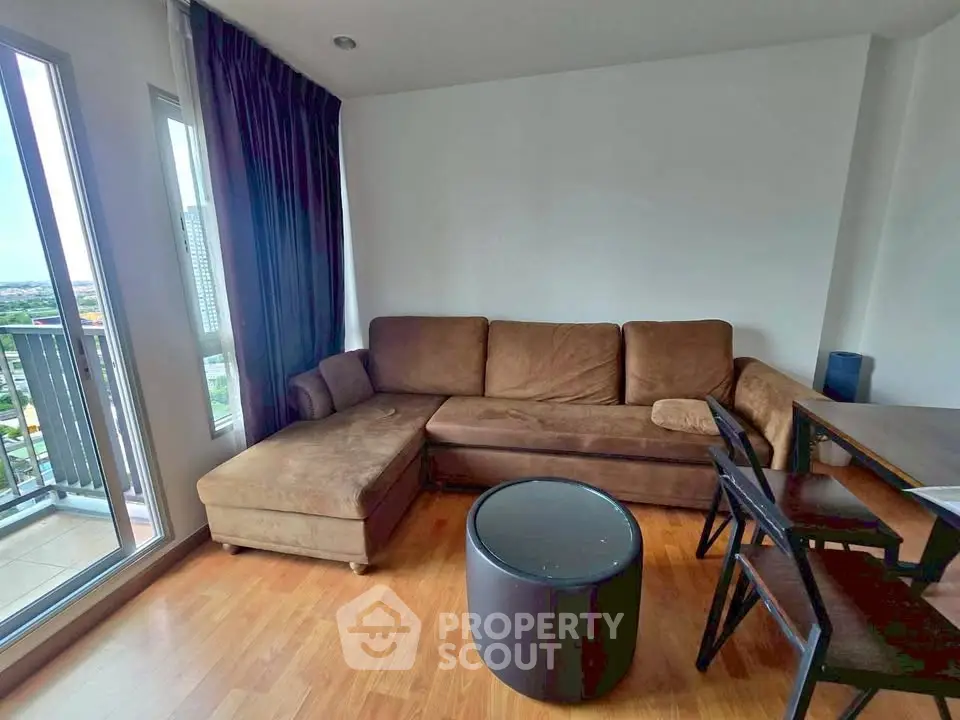 Cozy living room with brown sectional sofa and balcony view in modern apartment.