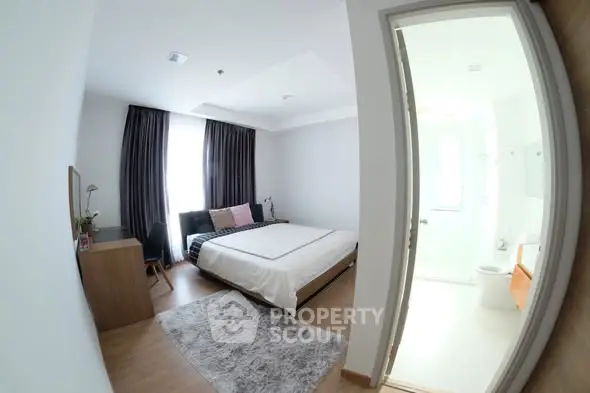 Spacious bedroom with modern decor and ensuite bathroom, featuring large windows and elegant furnishings.