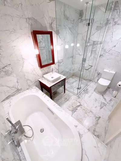 Luxurious marble bathroom with bathtub and glass shower enclosure