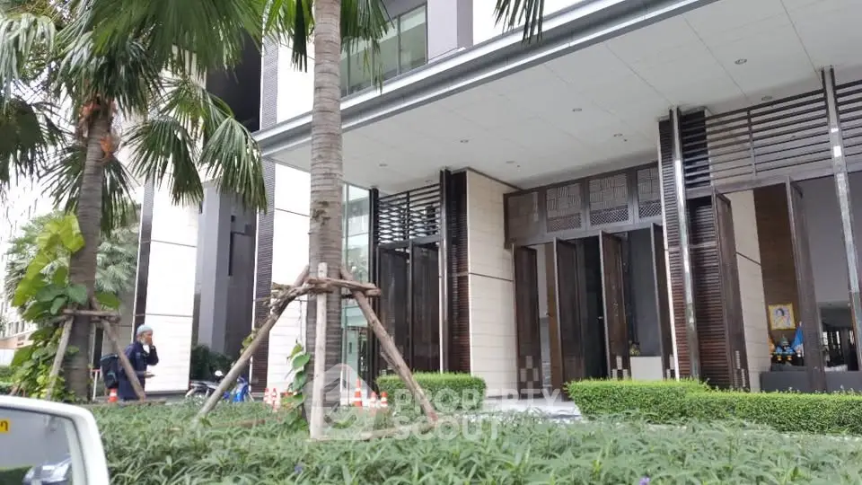 Modern building entrance with lush greenery and palm trees