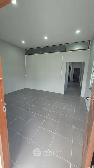 Spacious unfurnished room with tiled flooring and modern lighting, ideal for customization.