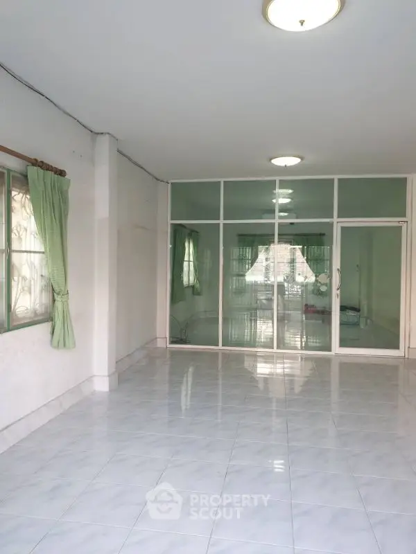 Spacious empty room with tiled floor and large windows, perfect for customization.