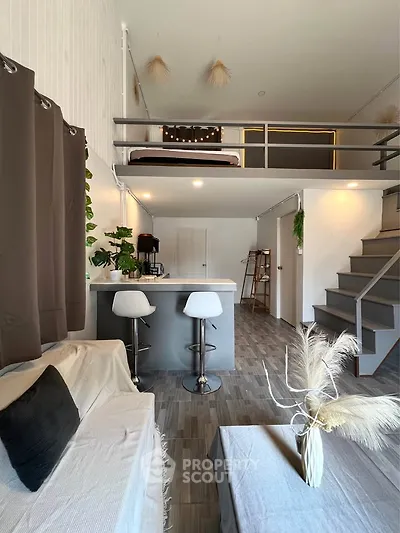 Modern loft apartment with stylish mezzanine and open living area, featuring sleek decor and natural light.