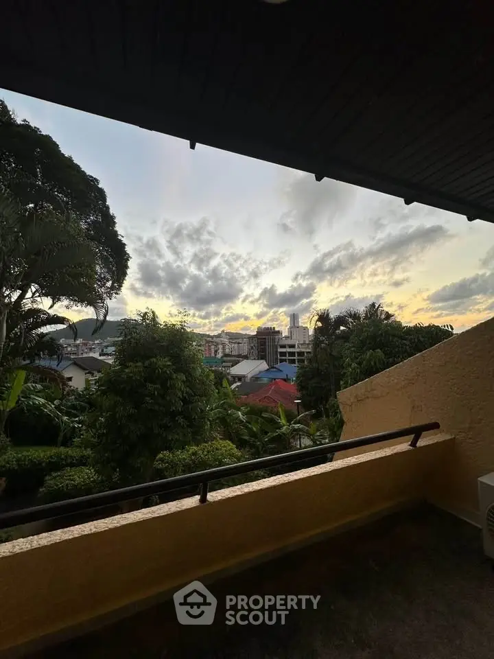 Stunning sunset view from a cozy balcony overlooking lush greenery and cityscape.