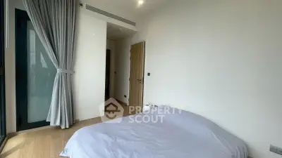 Modern bedroom with large window and minimalist decor in a high-rise apartment.