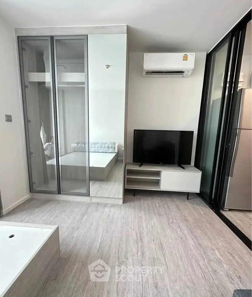 Modern living room with sleek design, featuring glass wardrobe, TV unit, and air conditioning.