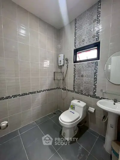 Modern bathroom with stylish tiles and essential fixtures in a real estate property.