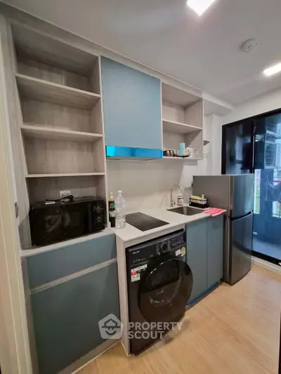 Modern kitchen with sleek cabinetry, washing machine, and compact fridge in a stylish apartment.