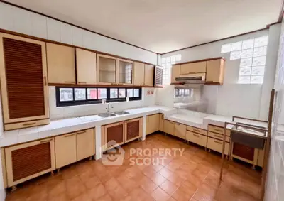 Spacious kitchen with wooden cabinets and tiled flooring, featuring ample natural light and a classic design.