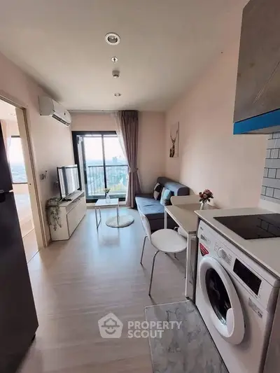 Modern living room with balcony view, stylish furniture, and in-unit washing machine in a cozy apartment.