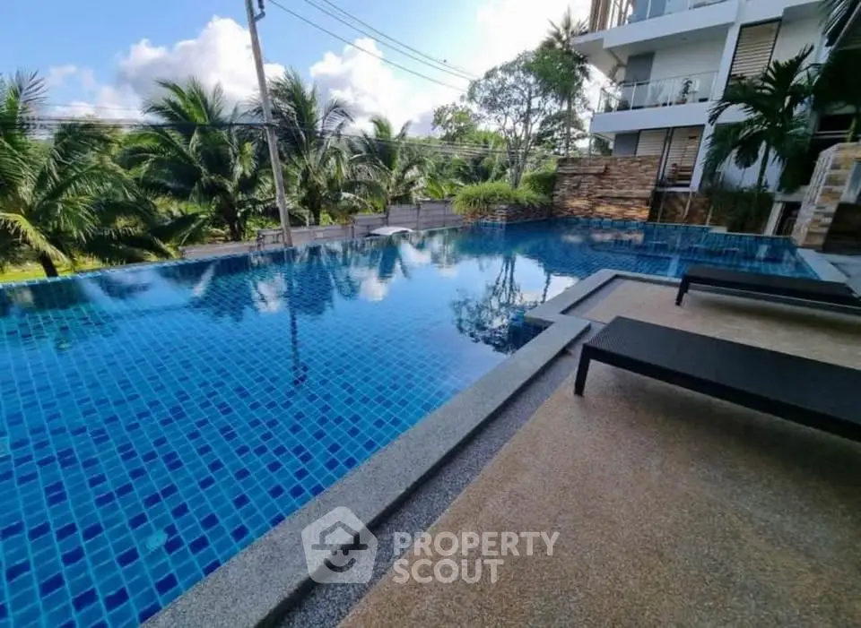 Luxurious poolside view with modern design and lush greenery in a tropical setting.