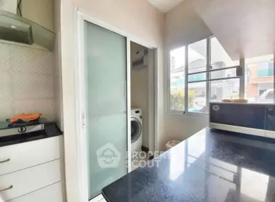 Modern kitchen with sleek countertops and adjacent laundry area featuring a washing machine.
