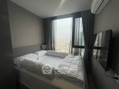 Cozy bedroom with panoramic city view, featuring modern decor and large windows for natural light.