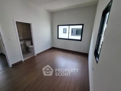 Spacious empty room with wooden flooring and large windows