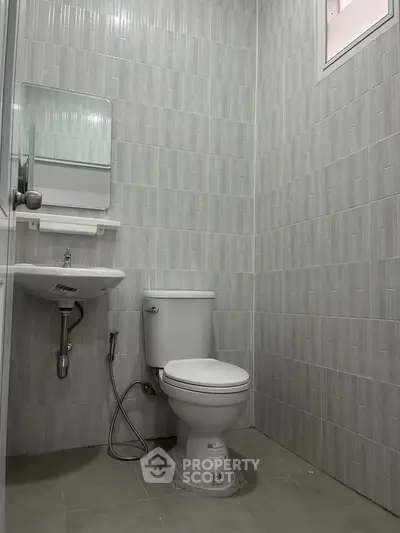 Modern bathroom with sleek gray tiles and compact design, featuring a toilet and sink.