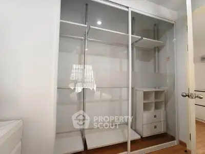 Spacious modern closet with sliding glass doors and built-in drawers in a bright room.
