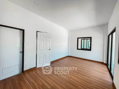 Spacious empty room with wooden flooring and white walls, ideal for customization.