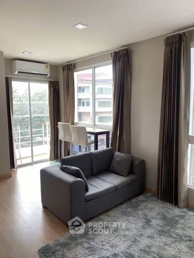 Modern living room with cozy sofa, large windows, and balcony access in a stylish apartment.