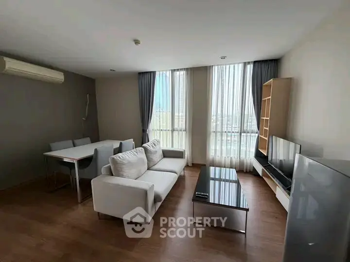 Spacious modern living room with large windows and stylish furniture in a high-rise apartment.