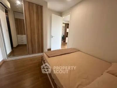 Cozy bedroom with wooden flooring and mirrored wardrobe in modern apartment.