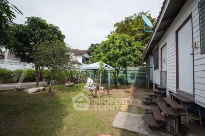 Charming backyard with lush greenery and cozy seating area, perfect for outdoor relaxation.