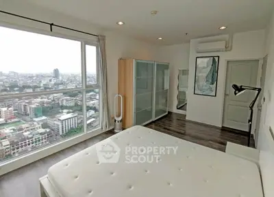 Spacious bedroom with city view, modern decor, and ample natural light in high-rise apartment.