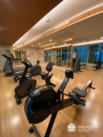 Modern gym with state-of-the-art fitness equipment and mirrored walls in luxury apartment complex.