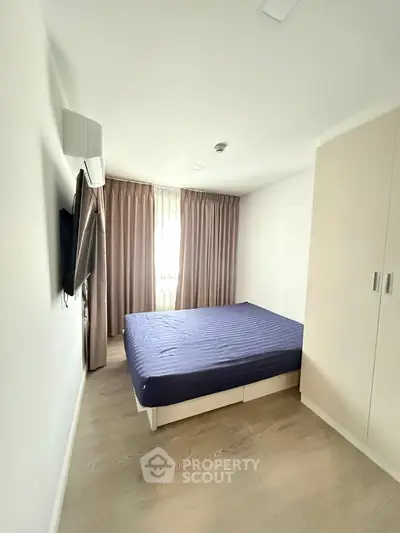 Spacious bedroom with modern design, featuring a large bed, built-in wardrobe, and natural light from a window.