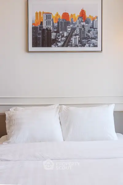 Elegant bedroom with modern cityscape artwork above a cozy white bed, perfect for urban living.