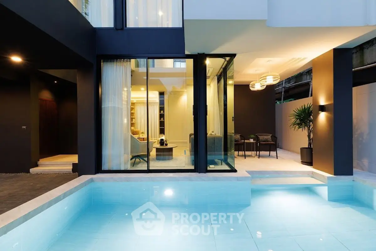 Luxurious modern home with poolside view and elegant interior lighting.