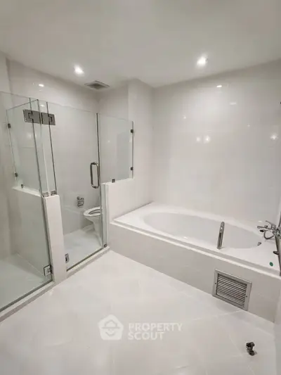 Spacious modern bathroom with glass shower and large bathtub, perfect for relaxation.