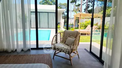 Luxurious bedroom with pool view and elegant outdoor seating area in modern villa.