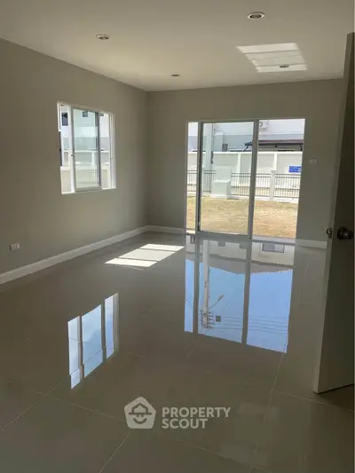 Spacious unfurnished room with glossy tiled floors and large windows offering natural light.