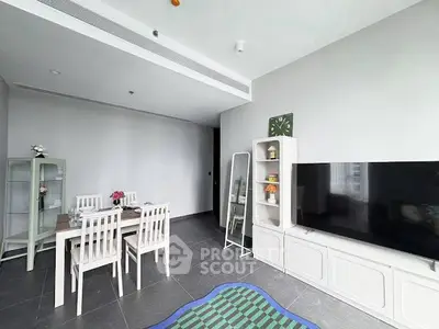 Modern living room with dining area, sleek furniture, and large TV in a stylish apartment.