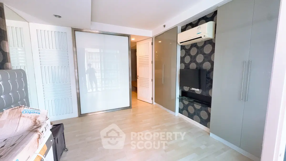 Modern bedroom with sleek design, featuring built-in wardrobe and air conditioning.