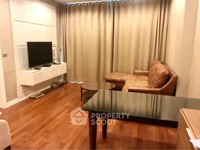 Spacious living room with leather sofa and modern TV setup, featuring elegant wooden flooring.