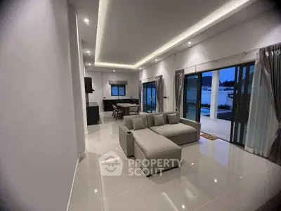 Spacious modern living room with sleek design and large windows opening to a patio.