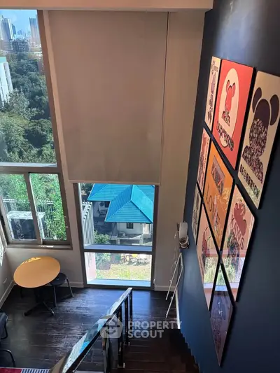 Stylish duplex interior with large windows and vibrant wall art, offering a stunning city view.