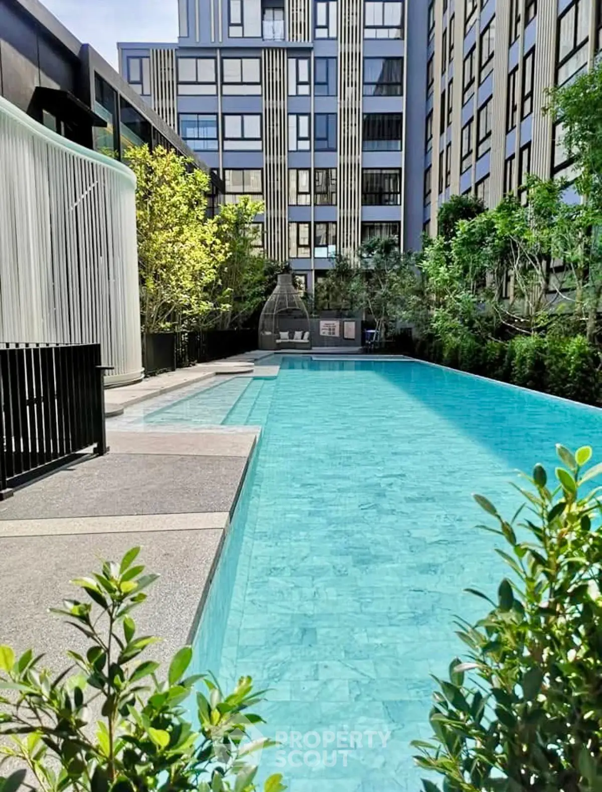 Luxurious modern apartment complex with stunning outdoor pool and lush greenery.