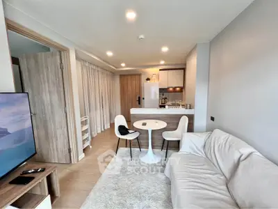 Modern living room with open kitchen, cozy sofa, and dining area in a stylish apartment.