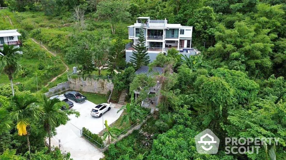 Stunning hillside villa with lush greenery and spacious parking area