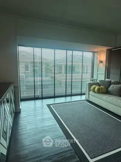 Modern living room with large windows and stylish decor, featuring a cozy sofa and elegant flooring.